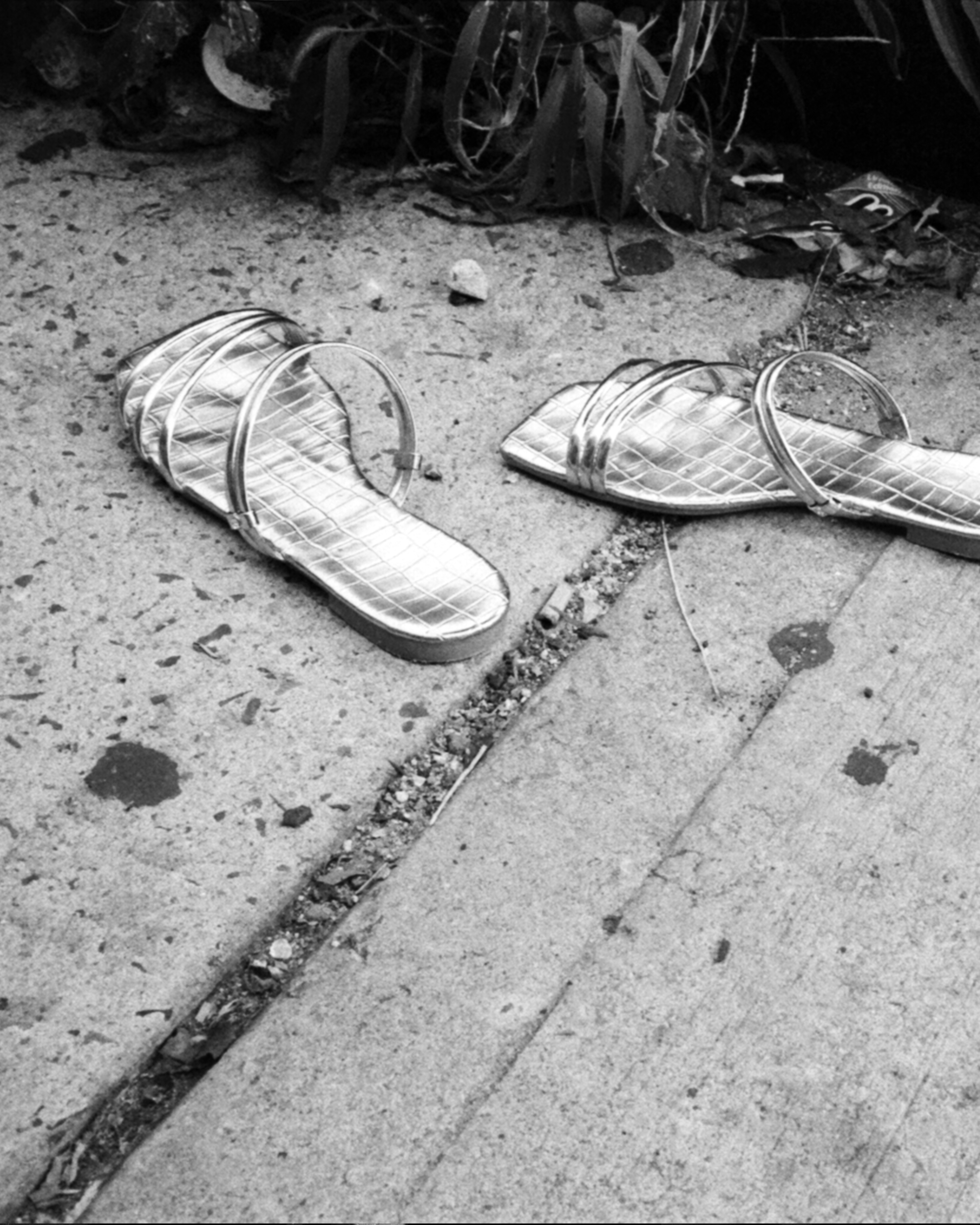 Photograph of pair of sandals on the sidewalk by Raul Barquet
